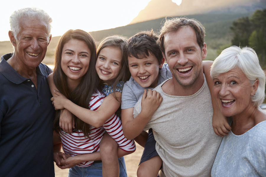 A multigenerational family smiles together outside