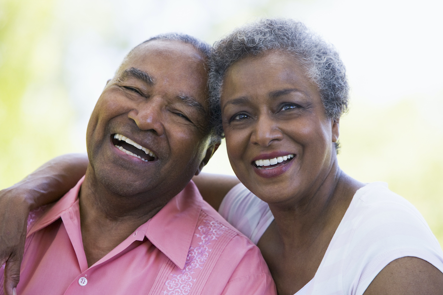 A Black older man and woman smile with their heads together after getting tooth replacements in Petaluma, CA