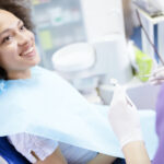 Black woman in a dental chair smiles at her dental hygienist during her dental cleaning appointment