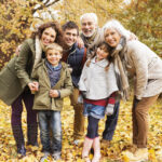 Photograph of a multigenerational family smiling in a park.