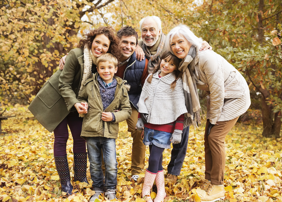 Photograph of a multigenerational family smiling in a park.