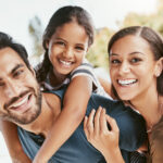 Photograph of Hispanic family (father, mother, daughter) with white smiles accompanying a dental blog about cosmetic dentistry.