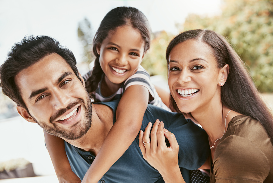 Photograph of Hispanic family (father, mother, daughter) with white smiles accompanying a dental blog about cosmetic dentistry.