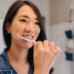 woman brushing her teeth or dental veneers for porcelain veneer care