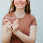 woman holding Invisalign clear aligners in a heart shape