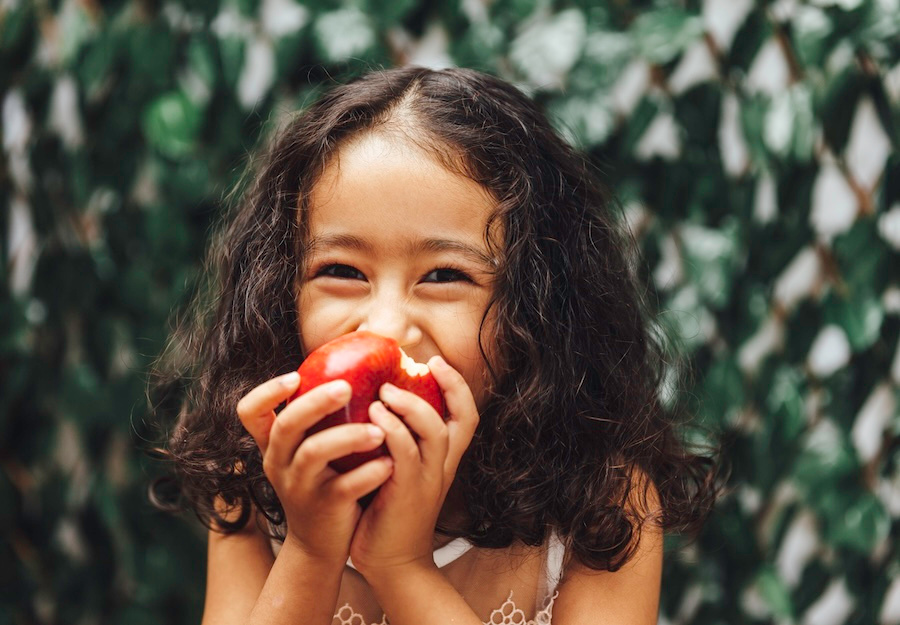 child eating a tooth-friendly snack, an apple