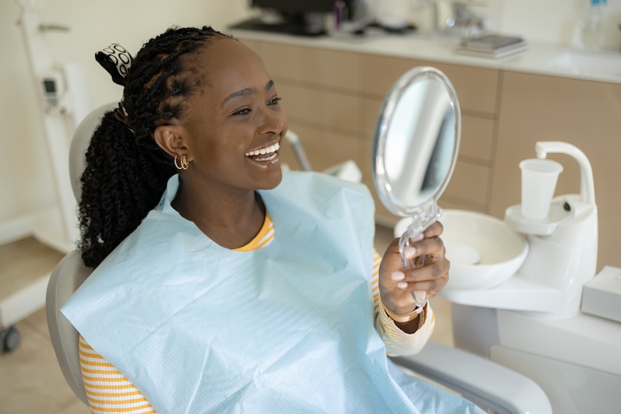 smiling woman in dental chair after cosmetic dentistry