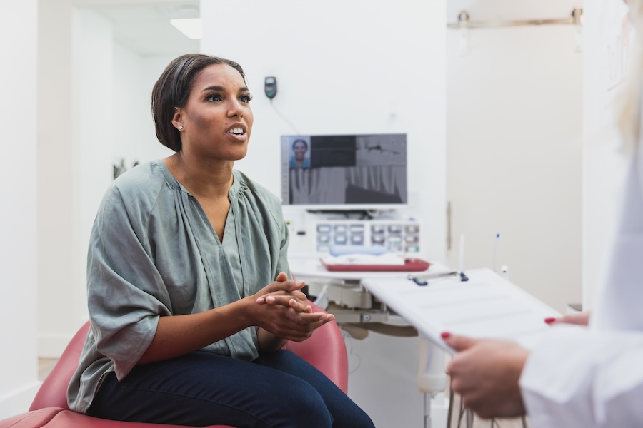 woman in dental chair asking dentist about metallic taste in mouth